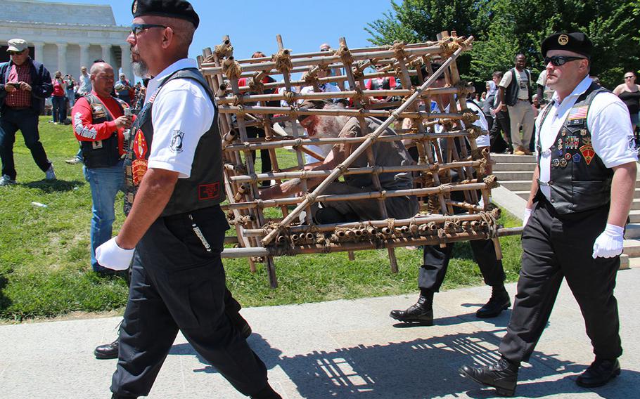 Chapter 3 VA Rolling Thunder Honor Guard carry Gerald McCullar to be placed in front of the Rolling Thunder demonstration stage to demonstrate as a POW trapped in a cage to show solidarity with comrades missing in action.