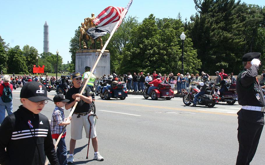 Brothers Michael Beene, left, and Patrick Beene of Burke, Va. take turns helping Navy Veteran Paul Stancliff hold the U.S. and POW/MIA flags to honor Rolling Thunder riders at the Memorial Bridge in Washington DC on May 26, 2013. Stancliff has participated in Rolling Thunder for 24 consecutive years.
