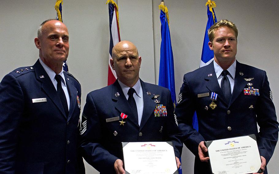 Lt. Gen. Craig Franklin, left, 3rd Air Force and 17th Expeditionary Air Force commander, awarded Master Sgt. Tracy Debbs, center, with a Bronze Star Medal with V device and Staff Sgt. Nicholas Miller, with a Distinguished Flying Cross with V device at RAF Lakenheath, England, on Wednesday, June 19, 2013. Debbs and Miller, both with the 56th Rescue Squadron, helped save 10 wounded coalition soldiers in Afghanistan last year.