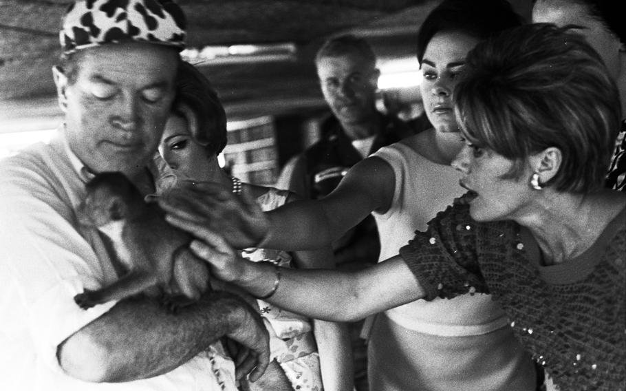 Bob Hope and members of his troupe meet the pet monkey of soldiers at Vinh Long.
