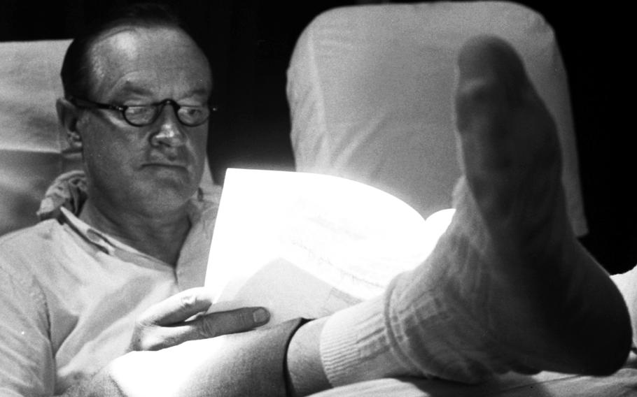 Bob Hope catches up on some paperwork during the flight to the next stop on his 1964 Christmas tour of Vietnam.
                