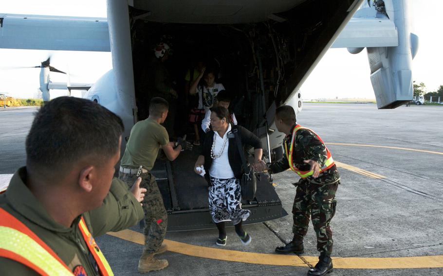 U.S. Marines guide a Filipino woman off an MV-22B Osprey and toward the terminal at Villamor Air Base Nov. 12, 2013. Typhoon Haiyan, the strongest typhoon recorded to make landfall has displaced hundreds of thousands in the Philippine Islands. 