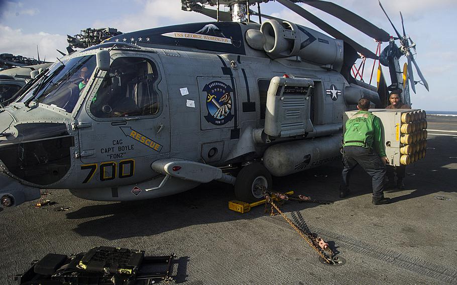 Sailors assigned to the Saberhawks of Helicopter Maritime Strike Squadron remove equipment from an MH-60R Seahawk helicopter aboard the USS George Washington as the carrier was en route to the Republic of the Philippines on Nov. 13, 2013, to support humanitarian efforts in response to Typhoon Haiyan.