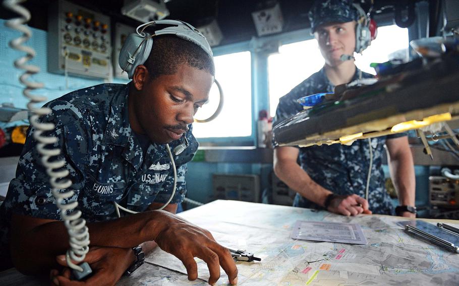 Petty Officer 3rd Class Juan Burns, assigned to the Ticonderoga-class guided-missile cruiser USS Antietam, reviews navigational charts in the bridge wing as the ship prepares to leave the port of Hong Kong on Nov. 12, 2013.