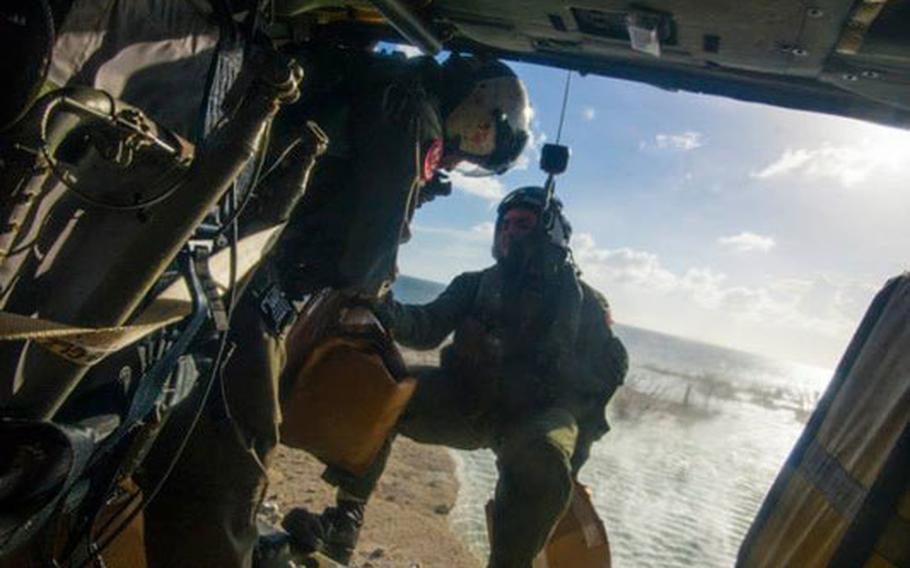 Petty Officer 2nd Class Justin Peach, right, from Riverside, Calif., prepares to drop supplies from an MH-60S Sea Hawk helicopter from the Golden Falcons of Helicopter Sea Combat Squadron 12, into Tacloban in support of Operation Damayan. 
