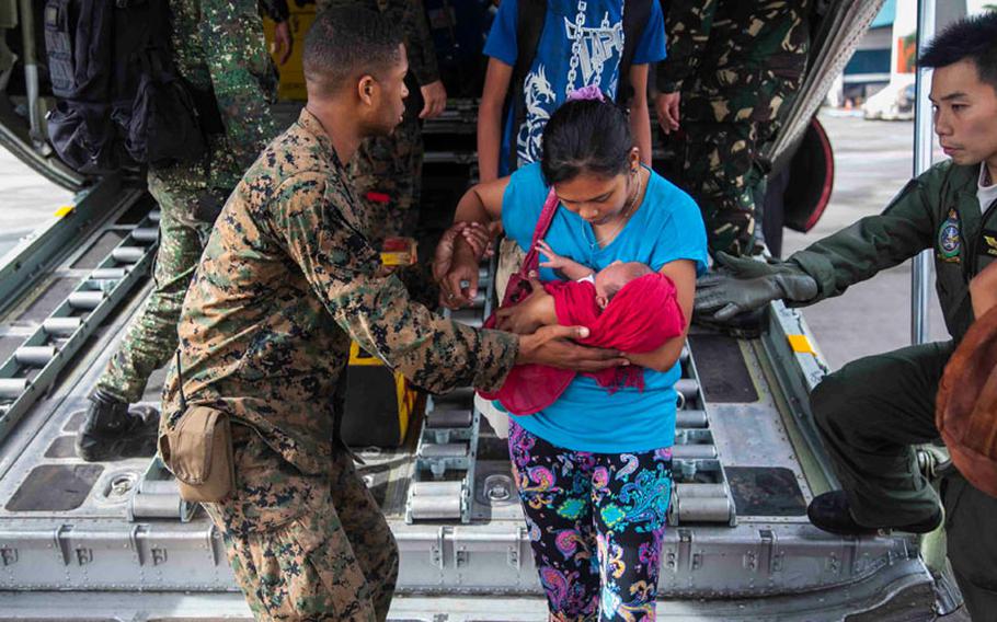 U.S. Marine Lance Cpl. Xavier L. Cannon and members of the Philippine Armed Forces help civilians displaced by Typhoon Haiyan disembark a C-130 aircraft Nov. 13 at Villamor Air Base as part of Operation Damayan.