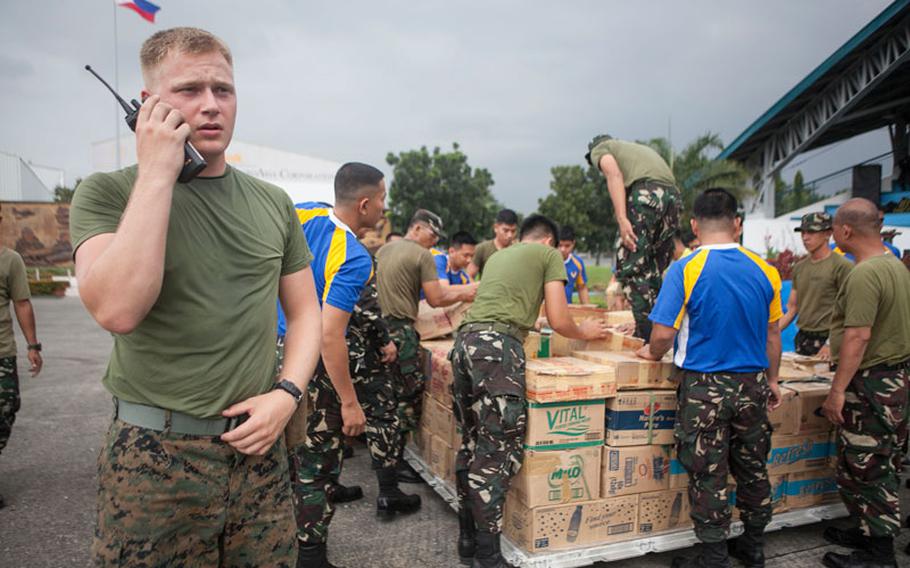 U.S. Marine Lance Cpl. Christopher E. Pring, a landing support specialist with Combat Logistics Regiment 3, currently assigned to 3d Marine Expeditionary Brigade, and a native of Tacoma, Wash., coordinates the loading of water with the Philippine Air Force for transportation at Villamor Air Base, Nov. 12.