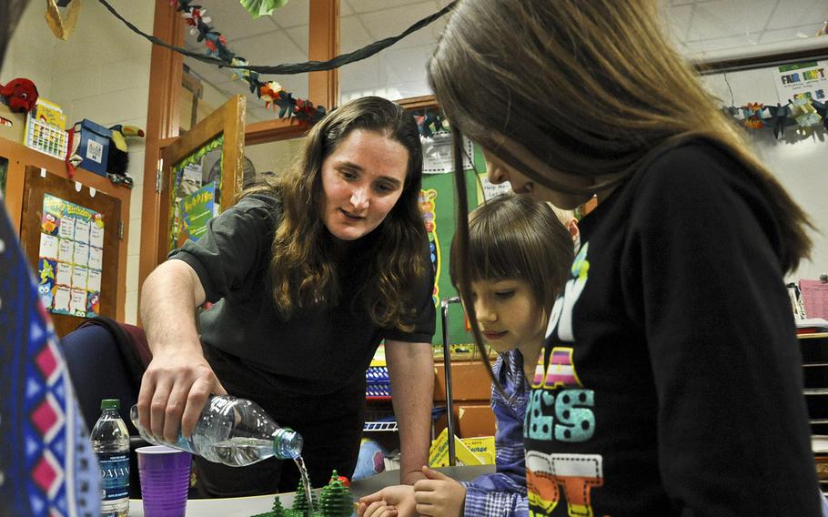 Magen McCollough, Williamsburg Environmental Group civil engineer, pours water over a simulated habitat to show the effects of water runoff during the Introduce a Girl to Engineering Day at John H. Russell Elementary School in Quantico, Va., in February 2012. The Pentagon has asked the RAND Corp. to study whether the DOD still needs to run schools in the United States.