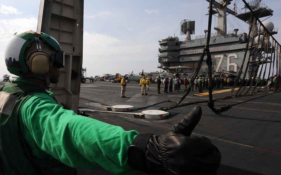 Morris Thomas gives the hand signal to raise the barricade stanchions during flight deck drills aboard the Nimitz-class aircraft carrier USS Ronald Reagan.