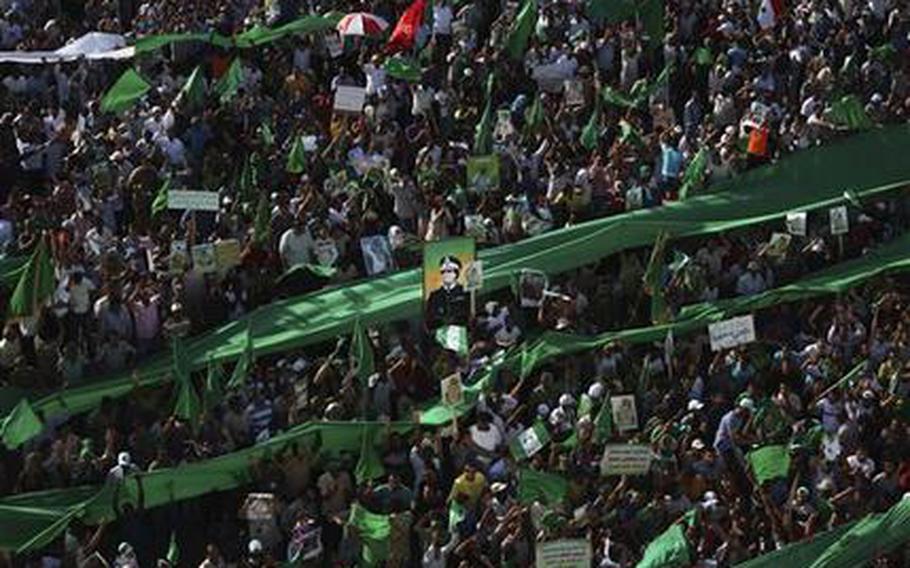 In this photo taken on a government-organized tour Friday, July 1, 2011, a Libyan man holds up a portrait of late Libyan leader Moammar Gadhafi during a rally in Green Square in downtown Tripoli, Libya. A ten year endeavor to eliminate the remnants of Lybia's former chemical weapons stockpile finally came to a close reporter the New York Times on Monday, February 03, 2014.