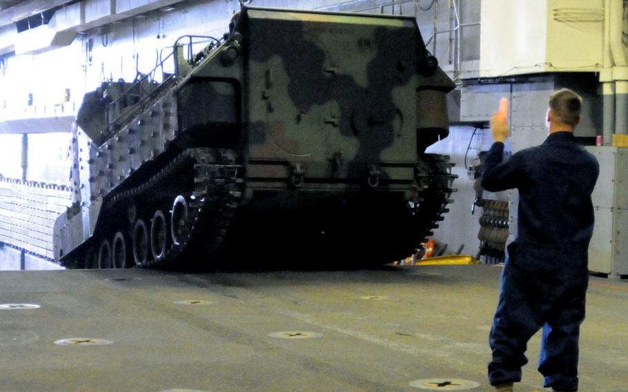 Marines and sailors move light armored vehicles on the USS Denver at White Beach Naval Facility, Okinawa, Feb. 4, 2014. Sailors from the Denver and members of the 3rd Marine Division are heading to Thailand in support of the upcoming Exercise Cobra Gold 2014.
                