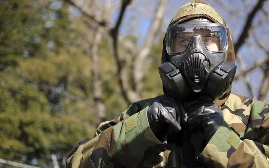 An airman from the 374th Airlift dons chemical protective wear in response to a simulated chemical warfare attack at Yokota Air Base during the base's Samurai Readiness Inspection March 5, 2014. 