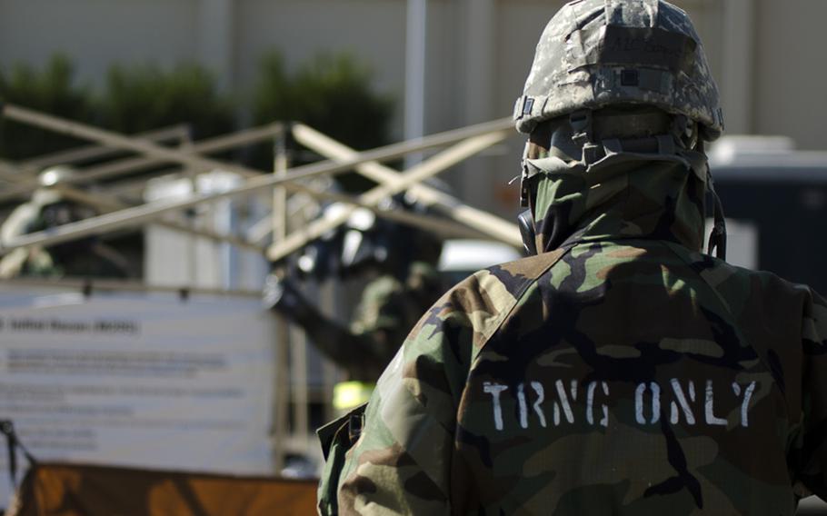 An airman from the 374th Airlift waits for deconamination following a simulated chemical warfare attack at Yokota Air Base during the base's Samurai Readiness Inspection March 5, 2014. 