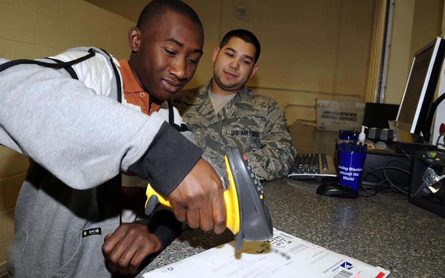 Jared Taylor, 16, scans a package under the guidance of Senior Airman Nolan Luna-Chavez at the RAF Mildenhall post office Aug. 3, 2012. Jared is part of the base's summer hire program, which allows students to work in clerical or labor positions around the base to assist military and civilian workers, earn money and gain workplace experience during their school break. (U.S. Air Force photo/Senior Airman )