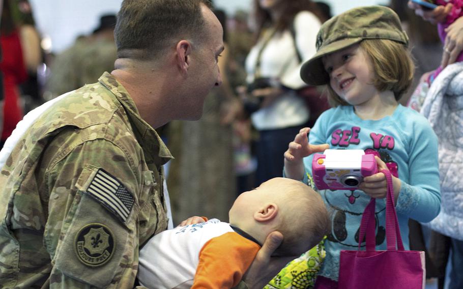 Capt. Riley Redus greets his daughter. Sierra, while holding his newborn son, Caleb John, for the first time after returning from a nine-month deployment to Afghanistan with the 2nd Cavalry Regiment, Monday, April 7, 2014.