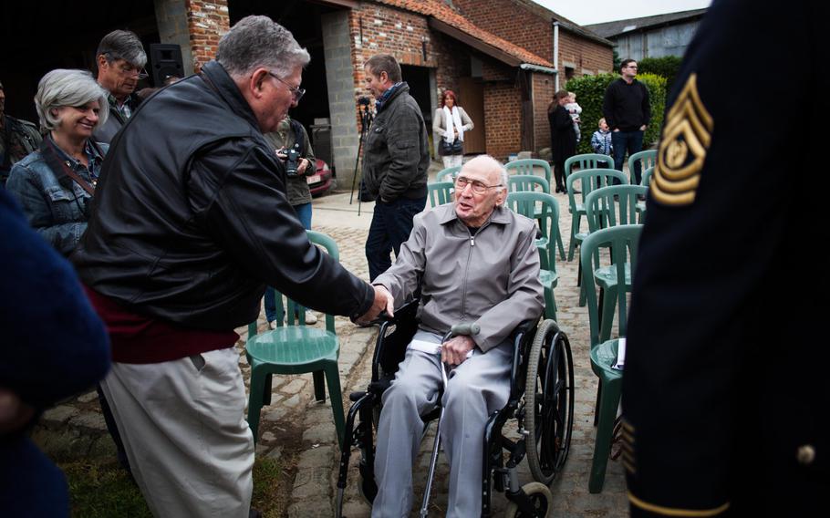 Albert Brady, whose father Lloyd Brady was killed in a plane crash during World War II, shakes hands with Troy Hollar, who managed with four other men to bail out. Hollar, Brady and about two dozen other family members of the crew went to Fouleng, Belgium, on Sunday, April 13, 2014, for a ceremony marking the 70th anniversary of the crash. 