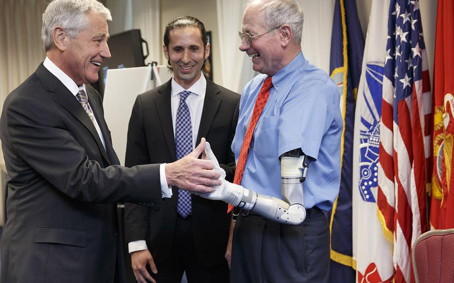 Defense Secretary Chuck Hagel, left, examines a prototype prosthetic arm and hand developed by DARPA, the Defense Advanced Research Projects Agency, fitted to Fred Downs, right, and explained by Justin C. Sanchez, center, a program manager with DARPA, Tuesday, April 22, 2014, at the Pentagon. Downs was wounded during the Vietnam War and served there with Hagel, who was getting a look at the latest high-tech projects being developed for wounded warriors. 