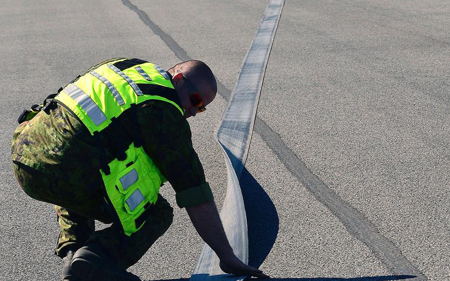 Barrier maintenance Airmen from Estonia and the U.S. measure the pull out length and inspect the purchase tape for damage after a certification barrier engagement at Amari Air Base, Estonia, April 22, 2014. Members of the 48th Air Expeditionary Group recently took a trip to Amari AB to engage and certify the aircraft arresting system, taking a critical step toward validating the new NATO Forward Operating Base. 
