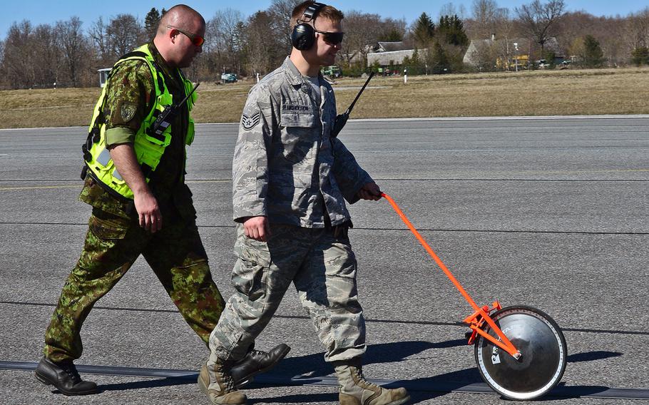 U.S. Air Force Staff Sgt. Josh Nicholson, 48th Air Expeditionary Group aircraft arresting systems craftsman and Estonian air force Master Sgt. Oleg Tsakuhhin, measure the pull out length of the purchase tape after a certification barrier engagement at Amari Air Base, Estonia, April 22, 2014. 