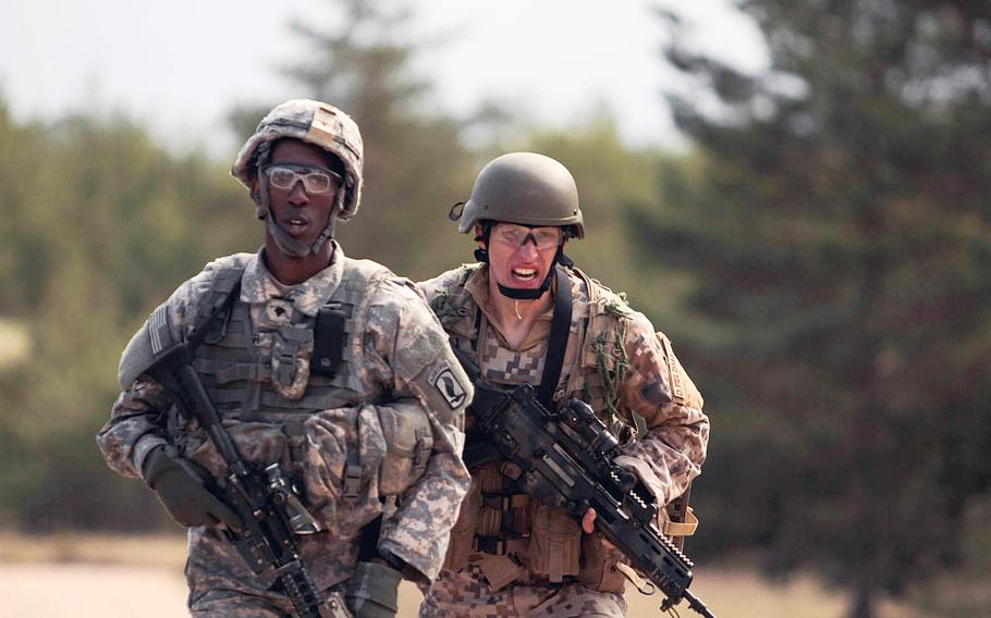 An American paratrooper from the 173rd Infantry Brigade Combat Team and a Latvian soldier sprint to the finish line Wednesday, April 30, 2014, during a stress shooting exercise that tested their endurance and marksmanship under rigorous physical conditions.