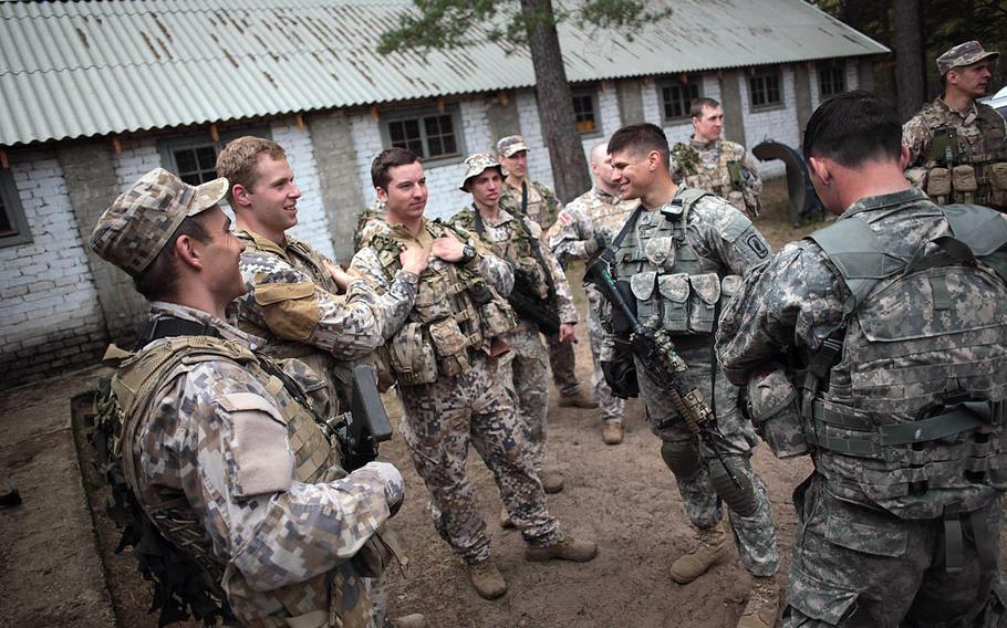 Latvian and American soldiers chat Wednesday, April 30, 2014, before being teamed up to run a stress shooting course that tested their endurance and marksmanship under rigorous physical conditions. 
                