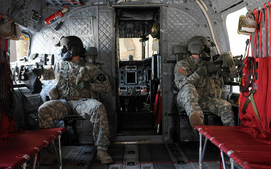 Two CH-47F crewmembers look out the Chinook's gunner hatch at Camp Humphreys, South Korea, on May 14, 2014. The soldiers are with the 3rd Battalion, 2nd Aviation Regiment.