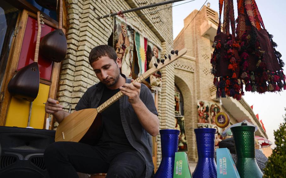 A musician plays an electric tanbur at the base of the Irbil Citadel in the center of the capital of Iraqi Kurdistan, entertaining passersby, Aug. 25, 2014.
                