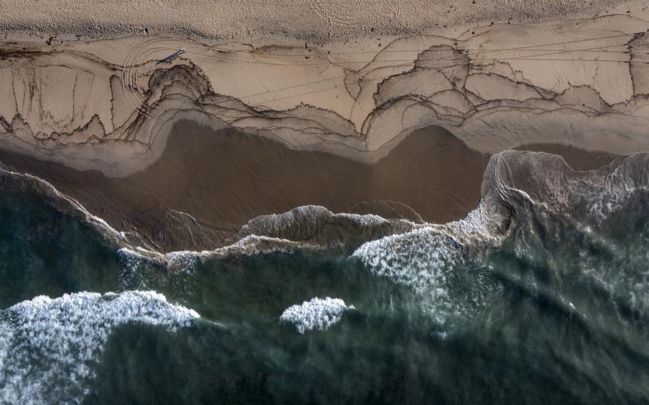 An aerial view of a major oil spill washing ashore with birds feeding at the water's edge on the border of Huntington Beach and Newport Beach at the Santa Ana River Jetties on Sunday, Oct. 3, 2021 in Huntington Beach, California. 