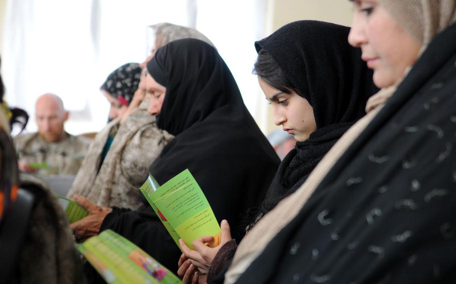 In this file photo from Dec. 6, 2012, an Afghan girl is seen reading a pamphlet provided by the provincial Director of Women's Affairs during a women's shura, or consultation, in Farah City, Afghanistan.