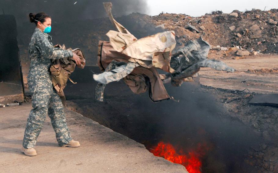Senior Airman Frances Gavalis tosses unserviceable uniform items into a burn pit at Balad Air Base, Iraq, on March 10, 2008.