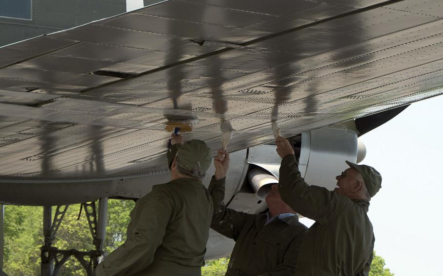 Members of the Texas Flying Legends Museum paint stripes on a plane at the Culpeper Regional Airport Thursday, May 7, during the preview for the Arsenal of Democracy: World WA maar II Victory Capitol Flyover.