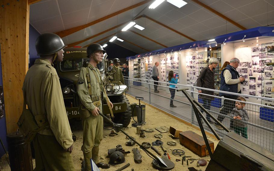 While visitors to the the Omaha Beach Memorial Museum in Saint-Laurent-sur-Mer, France, look at photos on display, a small boy checks out a display of minesweeping equipment. 