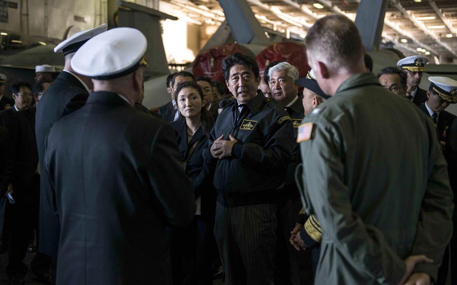Japanese Prime Minister Shinzo Abe, center, speaks to sailors aboard the aircraft carrier USS Ronald Reagan during a visit on Sunday, Oct. 18, 2015, while at sea in waters near Japan. Abe's visit marked the first time a sitting Japanese prime minister toured a U.S. aircraft carrier, Navy officials said.