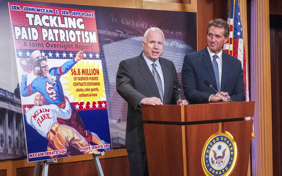 Arizona's two Republican Senators John McCain and Jeff Flake stand beside a billboard advertising the results of an investigative report questioning a Defense Department marketing program that doles out millions of dollars to various professional sports league teams to pay for patriotic tributes at games during a press event on Capitol Hill on Wednesday, Nov. 4, 2015.