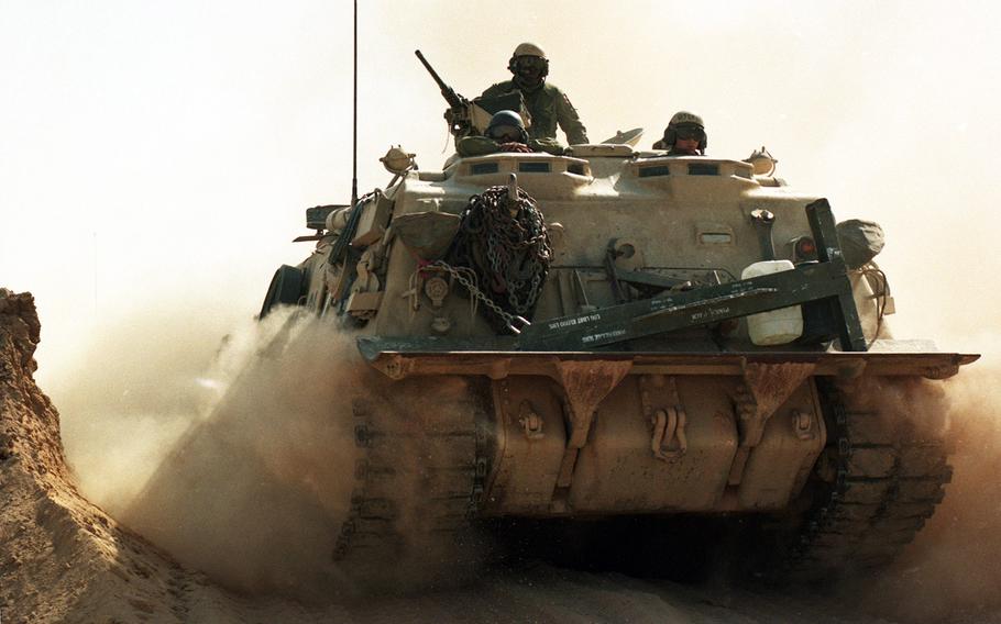 In February, 1991, an armored vehicle passes through a breached sand berm separating Saudi Arabia from Iraq, paving the way for advancing allied troops as the Gulf War moves to its next phase after 38 days of air raids and skirmishes.