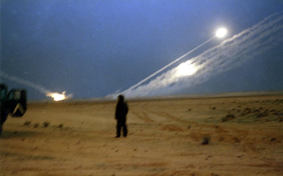 Multiple-Launch Rocket System (MLRS) rockets are fired toward Iraqi military units at dusk in southern Iraq during Operation Desert Storm in February, 1991. In the foreground is a soldier from Iron Troop, 2nd Armored Cavalry Regiment.