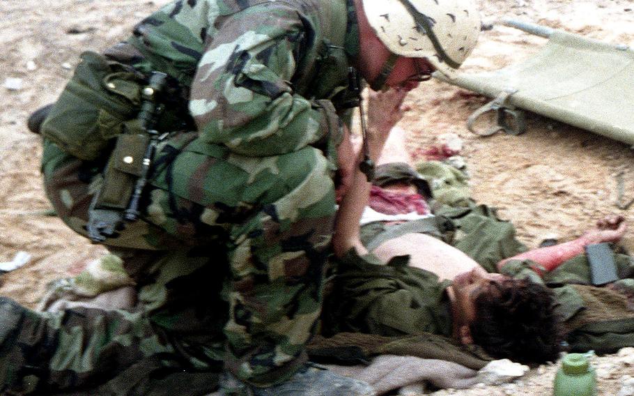 A wounded Iraqi soldier reaches up to touch the face of an American medic who's treating him after a battle in the desert during the Gulf War in February, 1991. Following this battle, the 2nd Armored Cavalry Regiment's Iron Troop took nearly 200 prisoners, some of whom reported that they had been in the desert for 46 days without sufficient food and water after being abandoned by the Republican Guard.