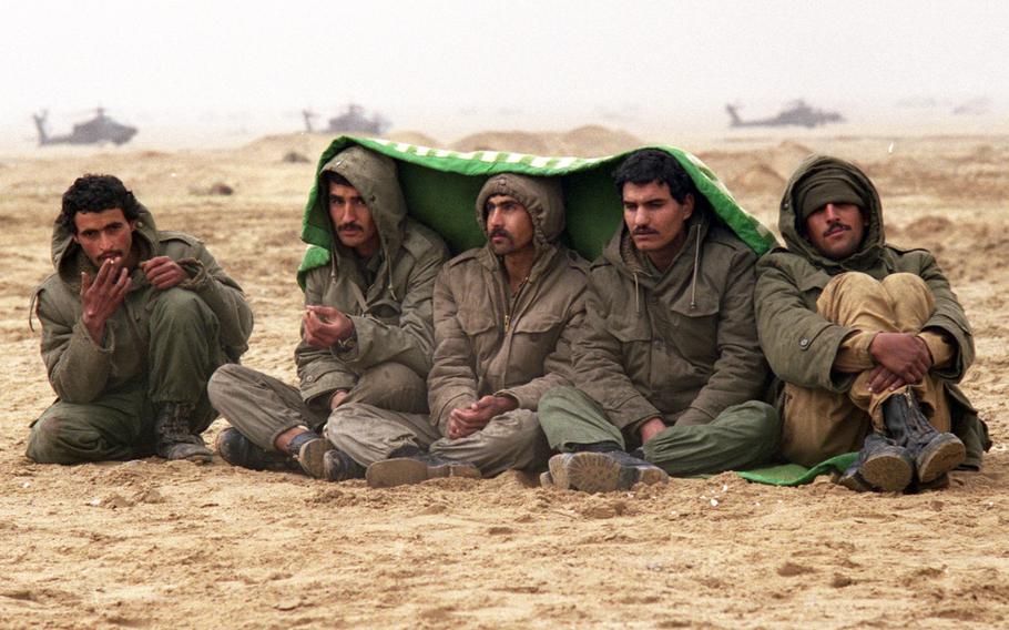 Iraqi prisoners of war attempt to stay warm as they await processing after their surrender to American troops from Iron Troop, 2nd Armored Cavalry Regiment in February, 1991.