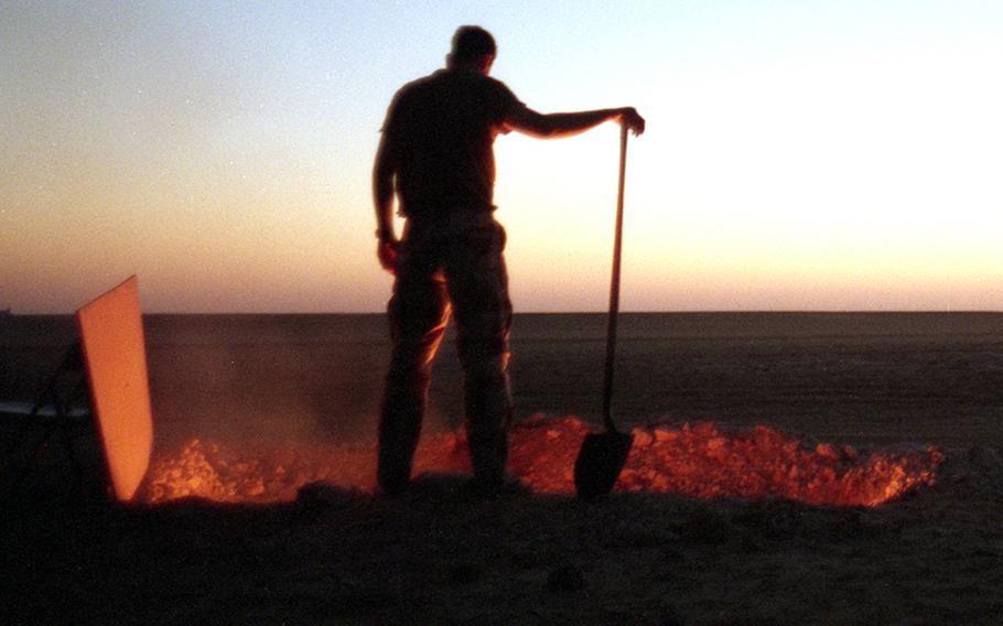 An American servicemember in the Saudi Arabian desert in 1991 tends a burning trash pit.