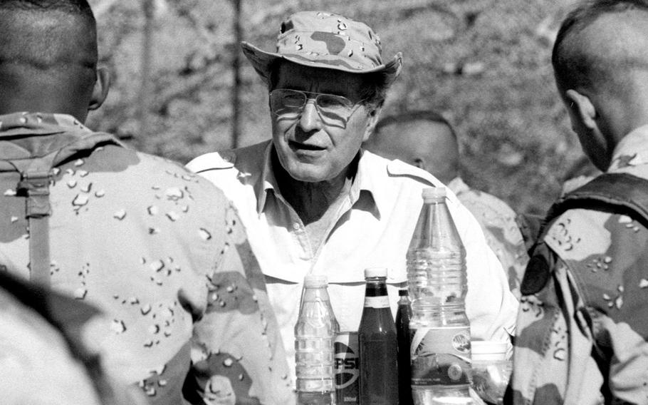 President George H.W. Bush shares a meal with troops in the Saudi Arabian desert during Operation Desert Shield in November, 1990.