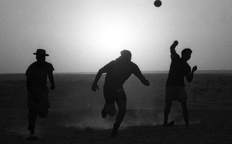 Three U.S. Marines are silhouetted against the setting sun as they play football in the Saudi Arabian desert in November, 1990, a few weeks before the start of the Gulf War.