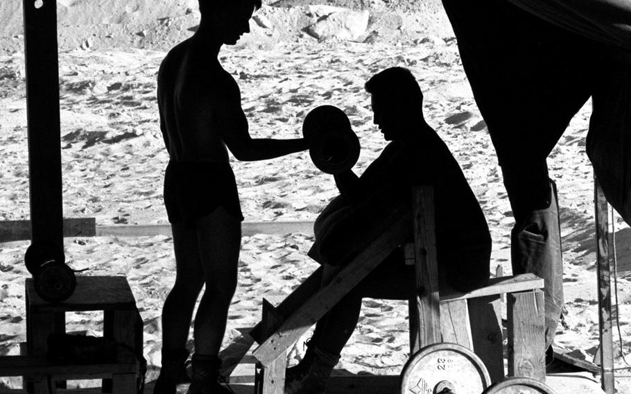 Two U.S. Marines stay in shape — and try to stave off boredom — by lifting weights in a makeshift gym in the Saudi Arabian desert in November, 1990.