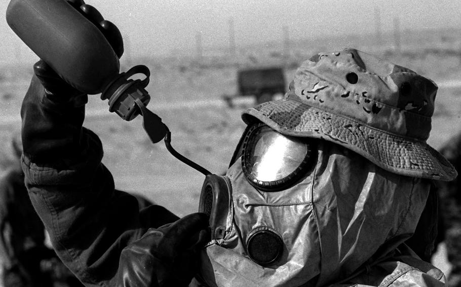 A U.S. Marine taking part in a chemical decontamination exercise in the weeks before the Gulf War gets some relief from the heat of his protective gear and the Saudi Arabian desert.