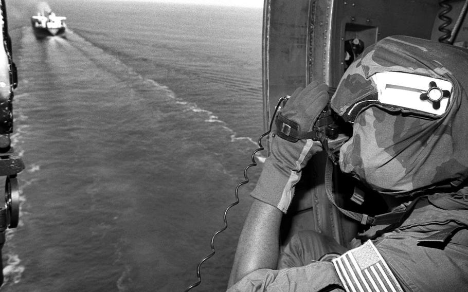 Petty Officer 3rd Class Sai Sharrieff, a UH-60 helicopter crewman, takes a close look at a Japanese tanker during intercept operations in the Gulf of Oman in November, 1990. The aircraft, from the USS Midway Battle Group out of Yokosuka Naval Base in Japan, was sending information on commercial ships back to the USS Fife amid the U.N. embargo of Iraq during the weeks leading up to the 1991 Gulf War.