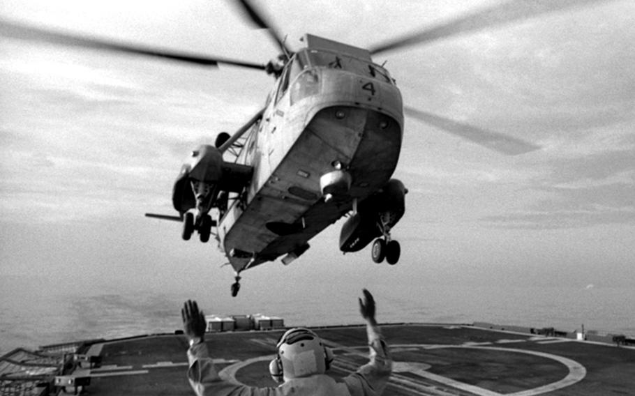A crewman guides an SH-3 Sea King helicopter onto the fantail of the destroyer USS Fife in the Gulf of Oman in November, 1990. The Fife, part of the USS Midway Battle Group from Yokosuka Naval Base in Japan, was spotting and intercepting commercial ships in enforcing the U.N. embargo of Iraq.