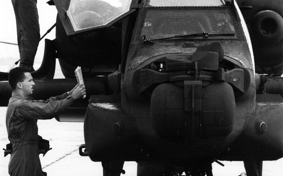At Wiesbaden, Germany, in August, 1990, Chief Warrant Officer 2 Paul R. Stein, top, and Chief Warrant Officer 2 David M. Conboy perform a pre-flight inspection of their Apache helicopter before departing for Italy and, eventually, Saudi Arabia. "We have trained in that type of environment, and it's great," Stein said of the desert destination. "There are no trees and no wires. Wires are a helicopter pilot's biggest nightmare."