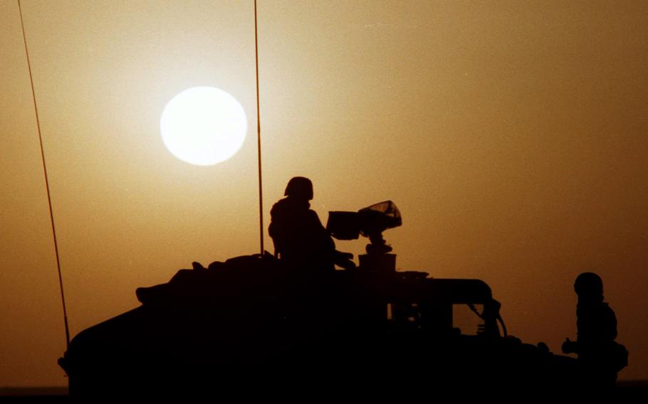 U.S. servicemembers are silhouetted against the desert sun in Saudi Arabia during Operation Desert Shield, the preface to the Gulf War.