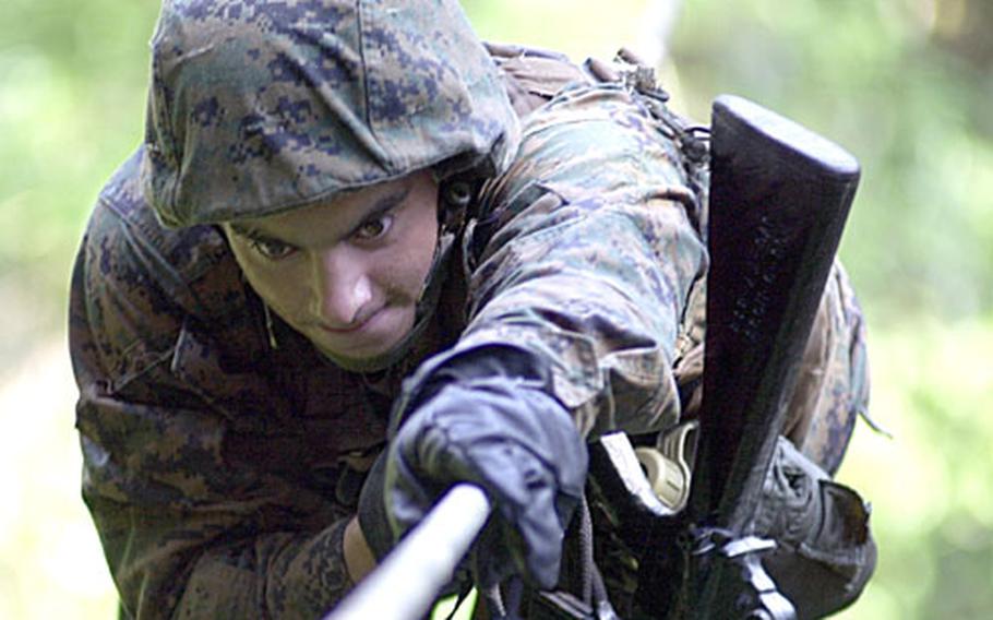 Lance Cpl. Joshua Rodriguez, 22, from Fredricksburg, Va., an administrative clerk with Marine Air Control Group 18, pulls himself across a rope bridge Friday at Commando Crawl, one of 31 obstacles on the endurance course at the Jungle Warfare Training Center on Camp Gonsalves. “It was a challenge, but I’m always up for a challenge,” said Rodriguez of the experience.