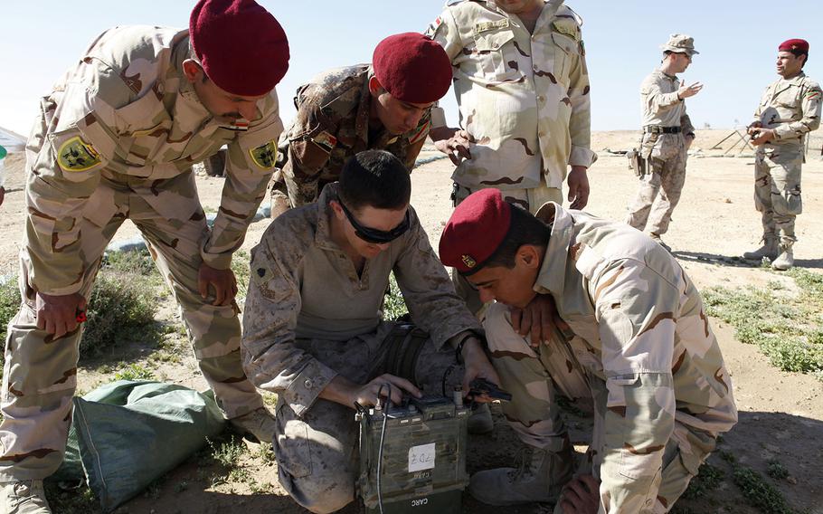A U.S. Marine, center, demonstrates how to conduct UHF radio operations for Iraqi Soldiers with the 7th Iraqi Army Division at Al Asad Air Base, Iraq, March 2, 2016. Communication training is just one of the skills taught at Al Asad as part of the building partner capacity mission, which increases the military capabilities of Iraqi Security Forces to fight the Islamic State.