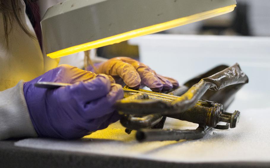 Naval History & Heritage Command lead conservator Shanna Daniel works on an artifact recovered from a 1942 shipwreck.
                